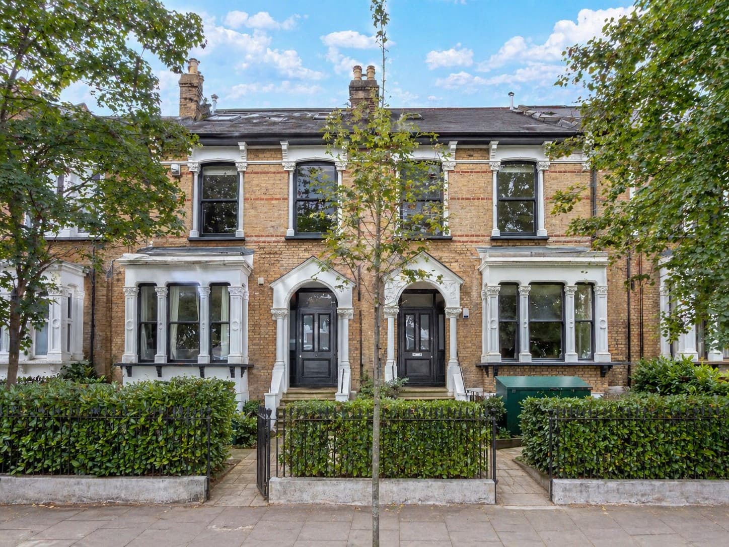 Two neighbouring restored Victorian terraces in Hackney, with white stucco detailing and arched doorways.